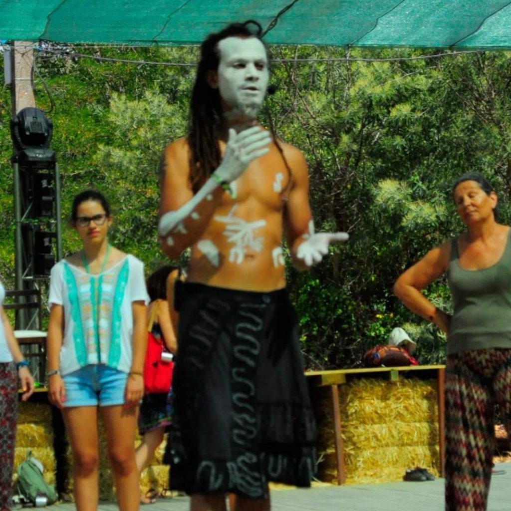 Facilitator with painted body art leading a workshop moment on an outdoor stage